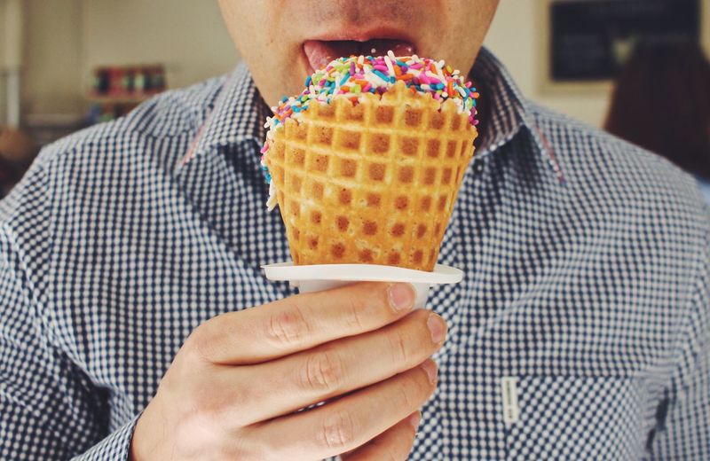Midsection of man eating ice cream cone