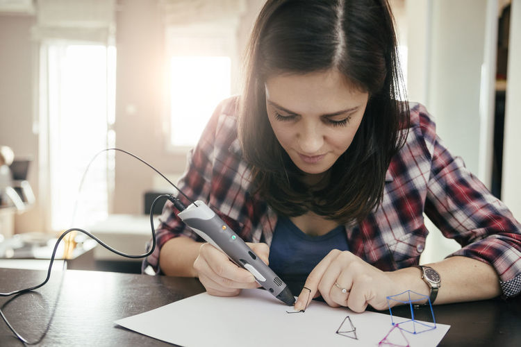 Young woman drawing with 3d pen