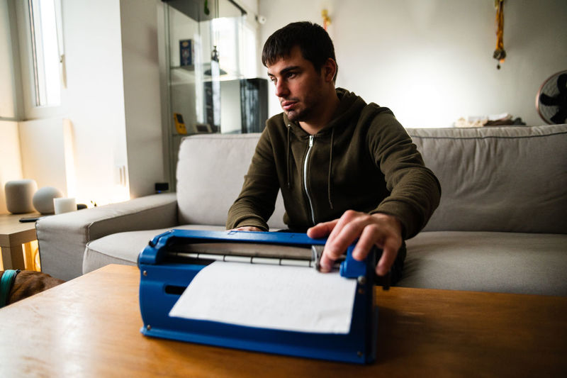 Visually impaired male typing on typewriter with tactile writing system at home