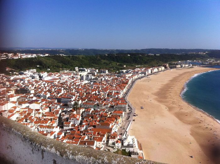 Aerial view of town by sea against clear blue sky