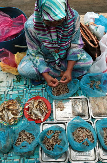 High angle view of woman cleaning prawns at fish market