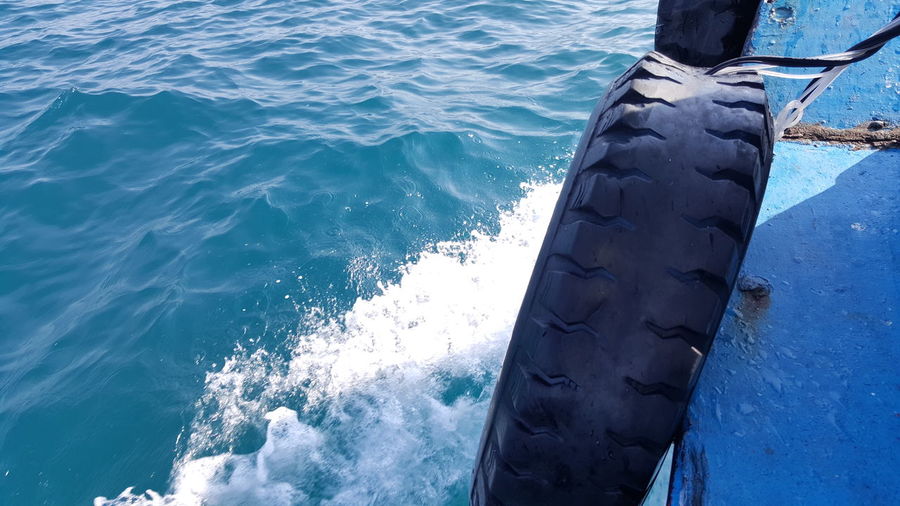 Cropped image of tire on boat in sea
