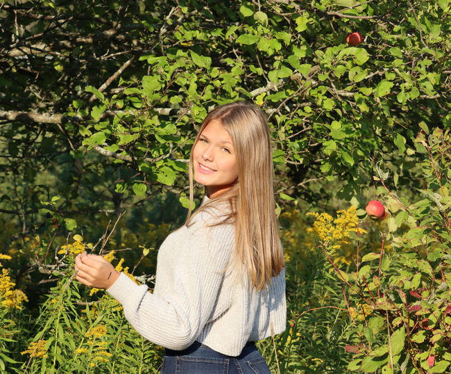 Portrait of smiling young woman against plants