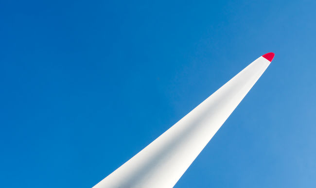 LOW ANGLE VIEW OF WIND TURBINE AGAINST BLUE SKY AND CLEAR BACKGROUND
