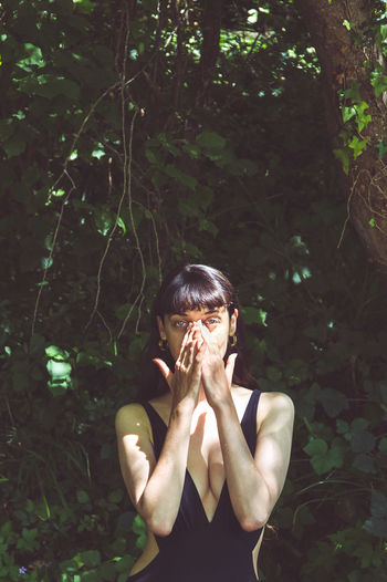 Portrait of woman in a forest covering face