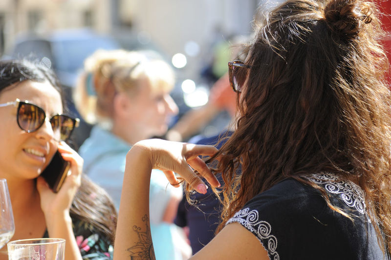 Brunette girl with sunglasses twisting her hair fingers showing puzzlement
