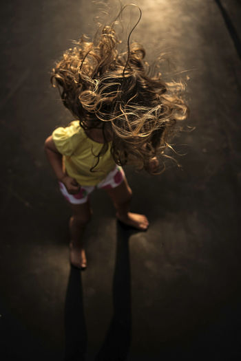 High angle view of girl with tousled hair standing on trampoline