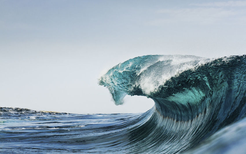 Breaking sea wave against clear blue sky