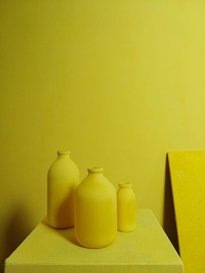 Close-up of yellow bottles on table against wall