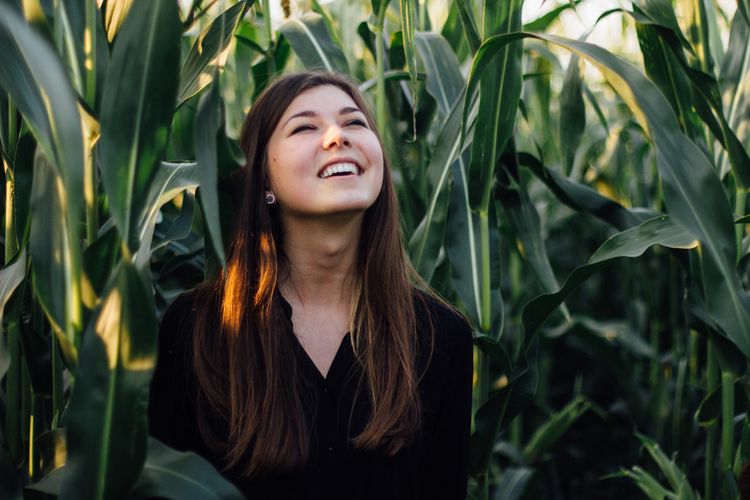 Young woman standing against crops on field