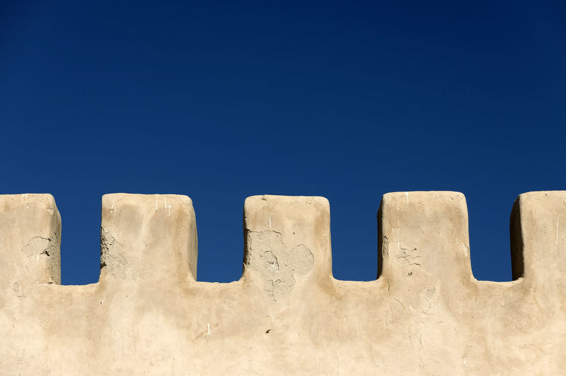 Low angle view of wall against clear blue sky