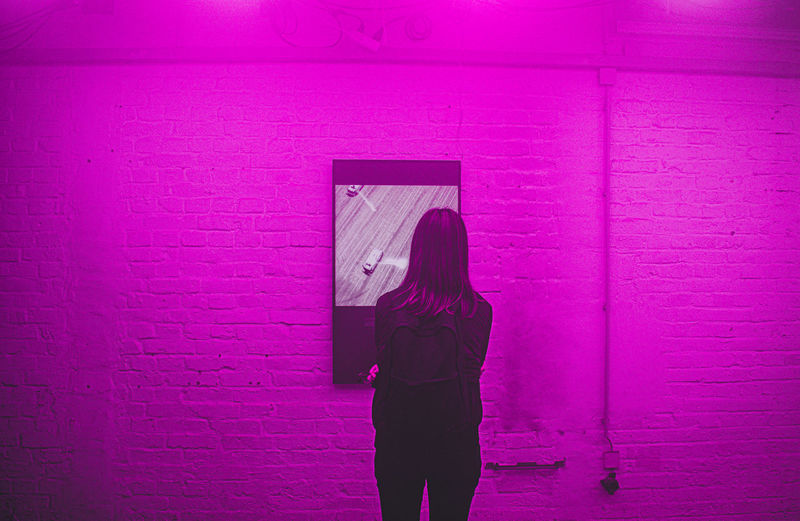 Rear view of woman standing against pink wall
