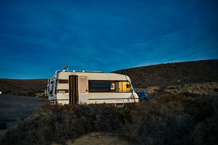 Vintage camper with opened door parked near hills against blue sky in evening in fuerteventura, spain