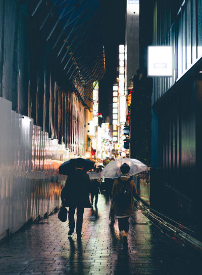 People walking on wet illuminated city