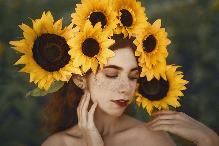 Close-up portrait of woman against sunflower