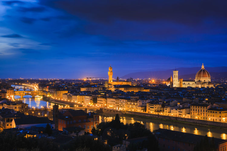 Aerial view of illuminated cityscape against blue sky at dusk