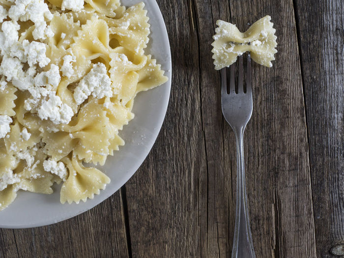 Close-up of farfalle pasta with cheese in plate on wooden table