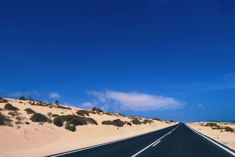 Road on desert against clear blue sky