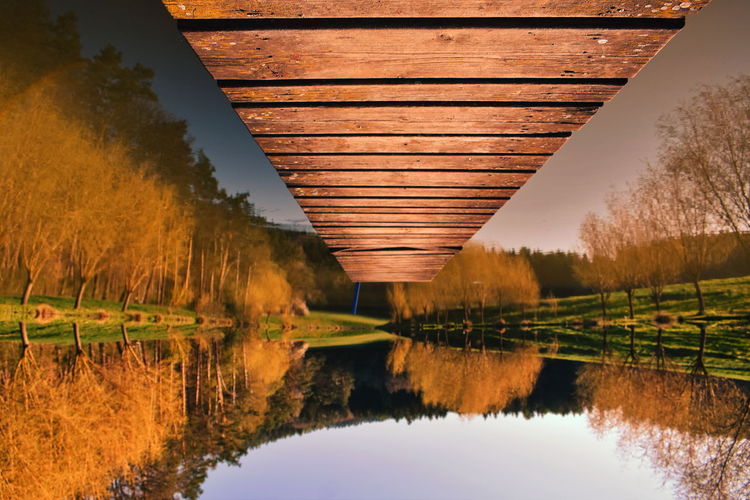 Reflection of bridge on lake against sky