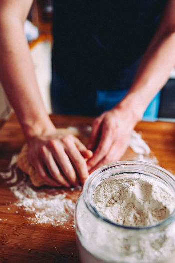 Midsection of person kneading dough in kitchen