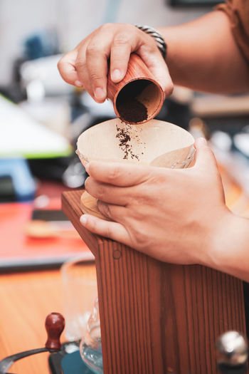 Cropped hands of woman pouring coffee powder in container