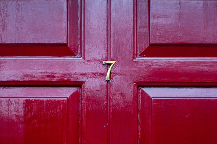 House number 7 on a red wooden front door in london 
