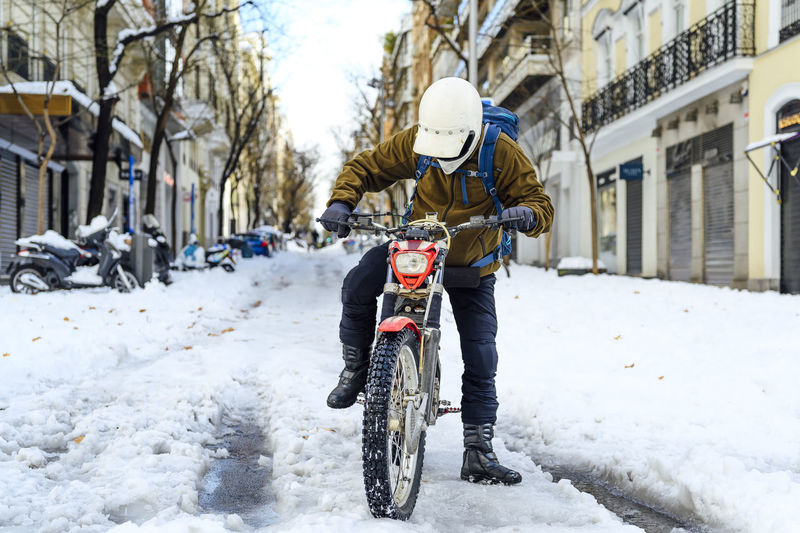 Man with bicycle on snow in city