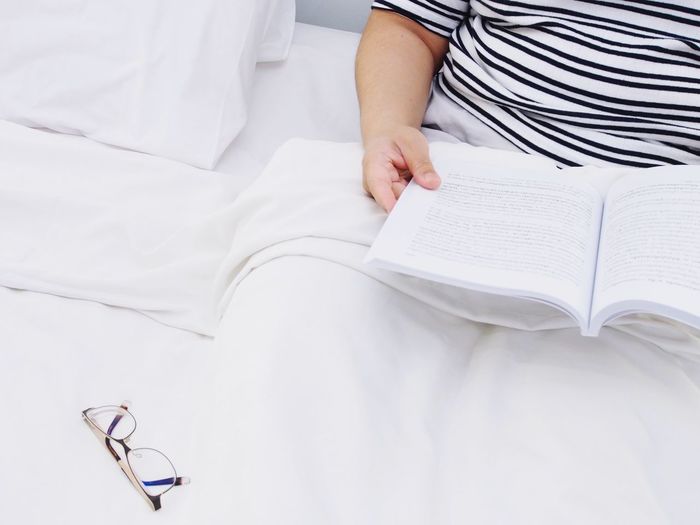High angle view of woman reading book on bed