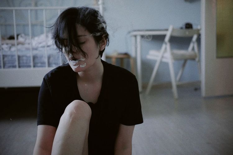 Side view of young woman sitting at home