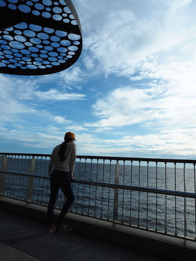 Full length of man standing on railing against sea