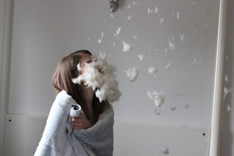 Woman with feathers flying in room