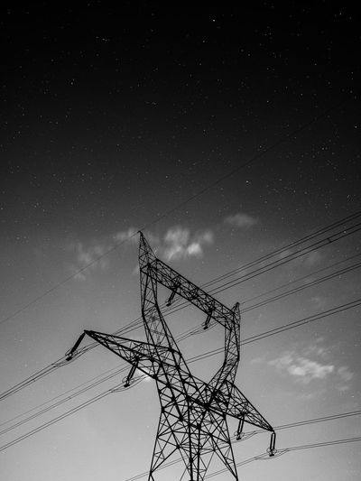 Low angle view of electricity pylon against sky at night