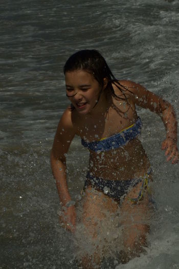 Cheerful smiling teenage girl playing in sea
