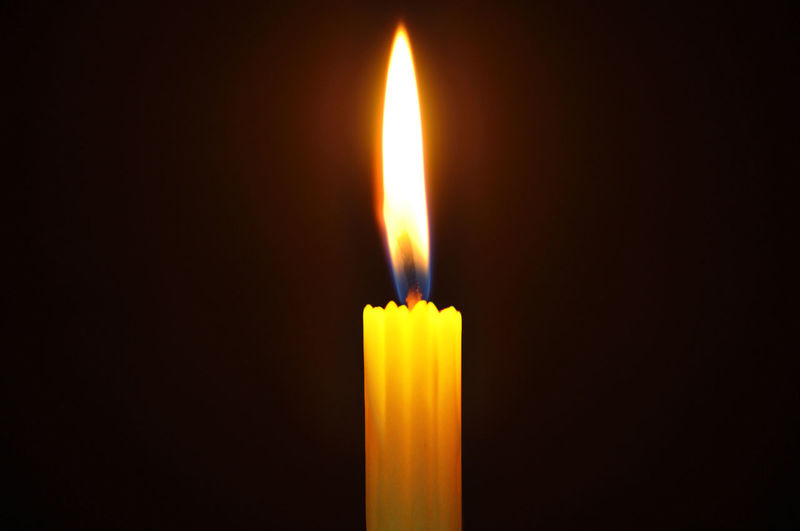 Close-up of lit candle against black background