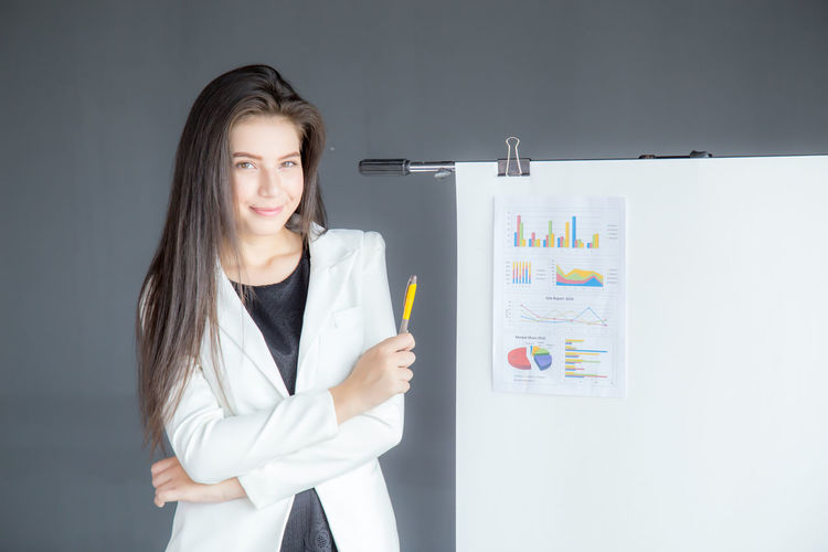 Portrait of smiling businesswoman standing by flipchart at office