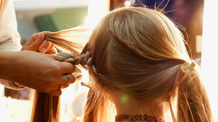 Cropped hands of female hairstylist styling girl hair
