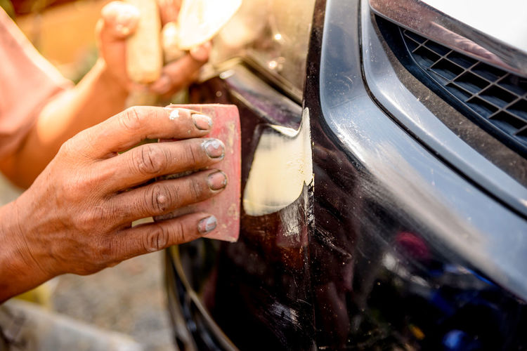 Cropped image of worker scrubbing car with scrapper