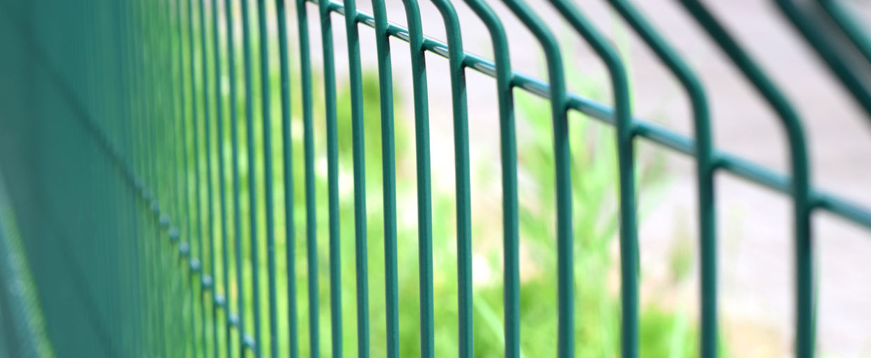 Green steel wire fence with rods. protecting private property. selective focus