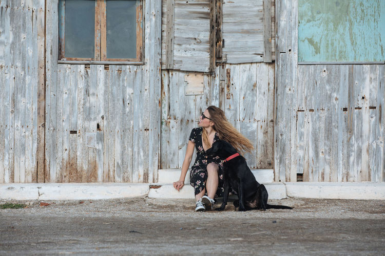 Woman sitting with dog against old house
