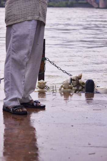 A man feet wearing white pijama standing by ganga river and god sculpture in haridwar