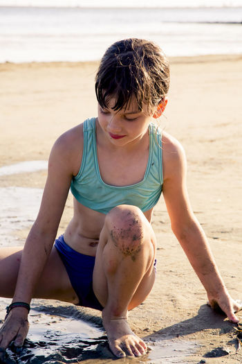 Girl in swimwear playing with sand at beach