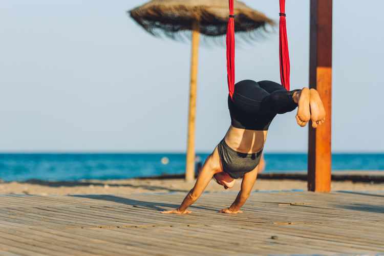 Full length of man relaxing on pier at beach against sky