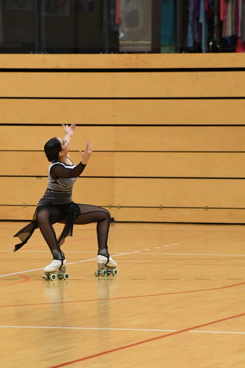 Full length of young woman roller skating while dancing on hardwood floor
