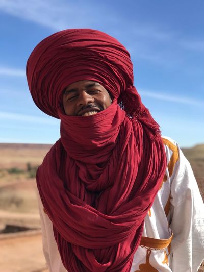 Smiling man in traditional clothing standing against sky