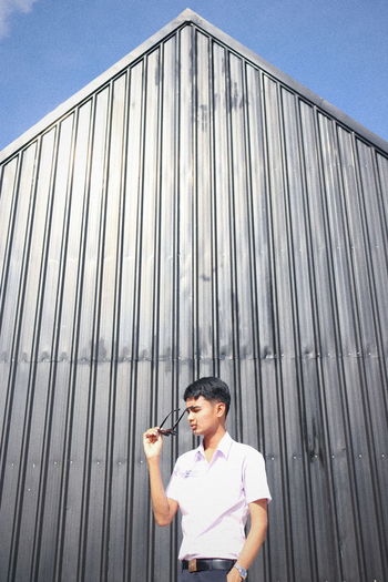 Young man standing against metal structure