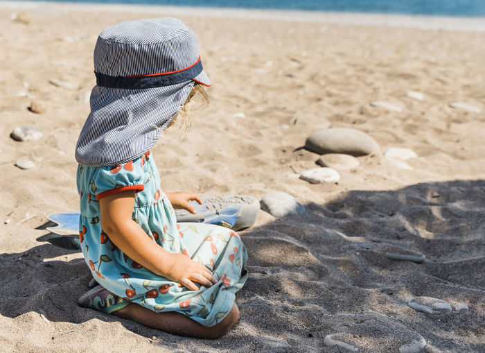 Rear view of girl sitting on sand at beach