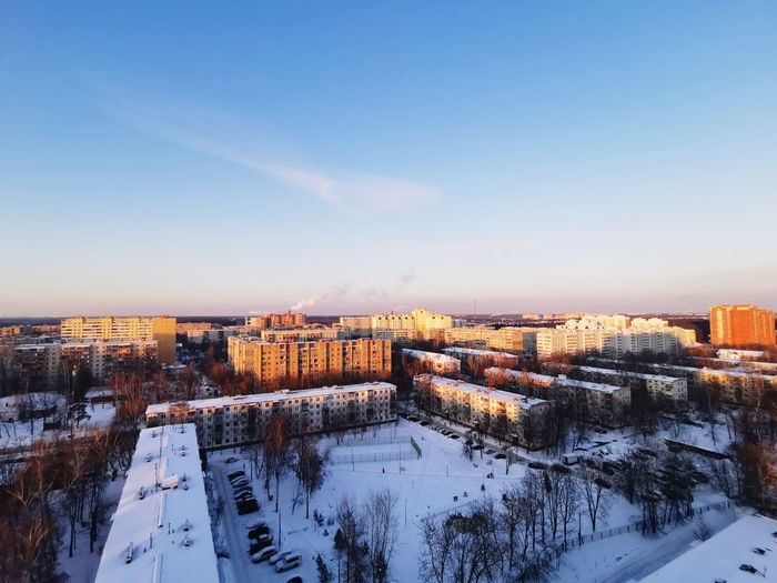 High angle view of snow covered buildings against sky during sunset