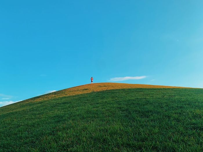 Low angle view of woman standing on mountain against sky