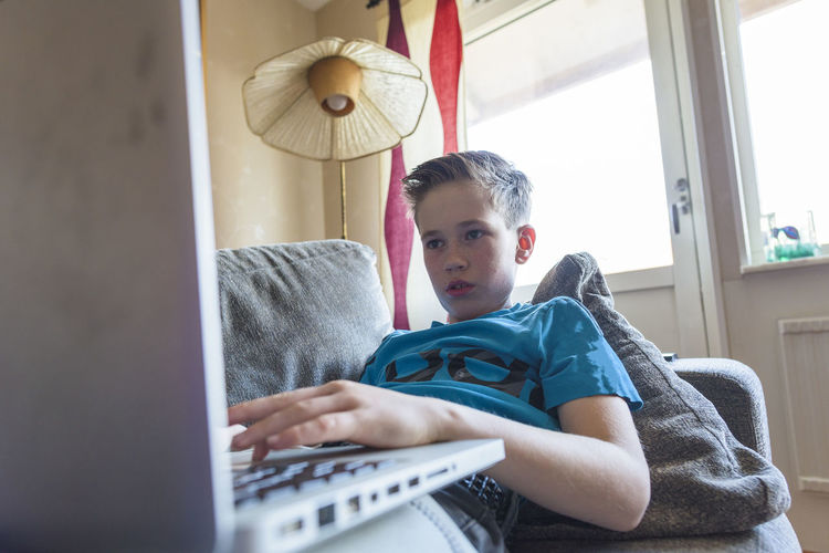 Boy using laptop on sofa