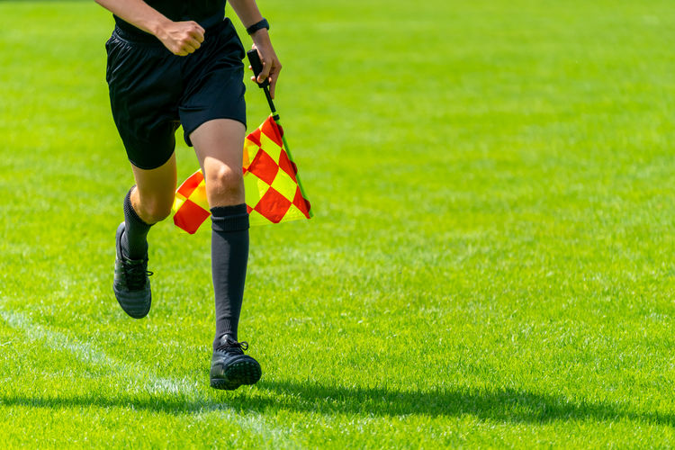 Low section of man holding flag while running on grassy field